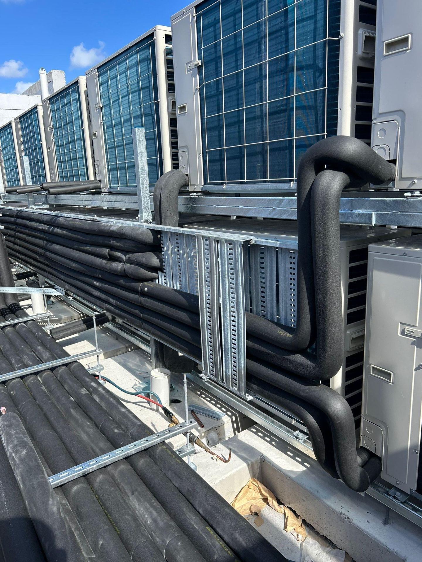 Row of rooftop condensing units connected with insulated refrigerant pipework